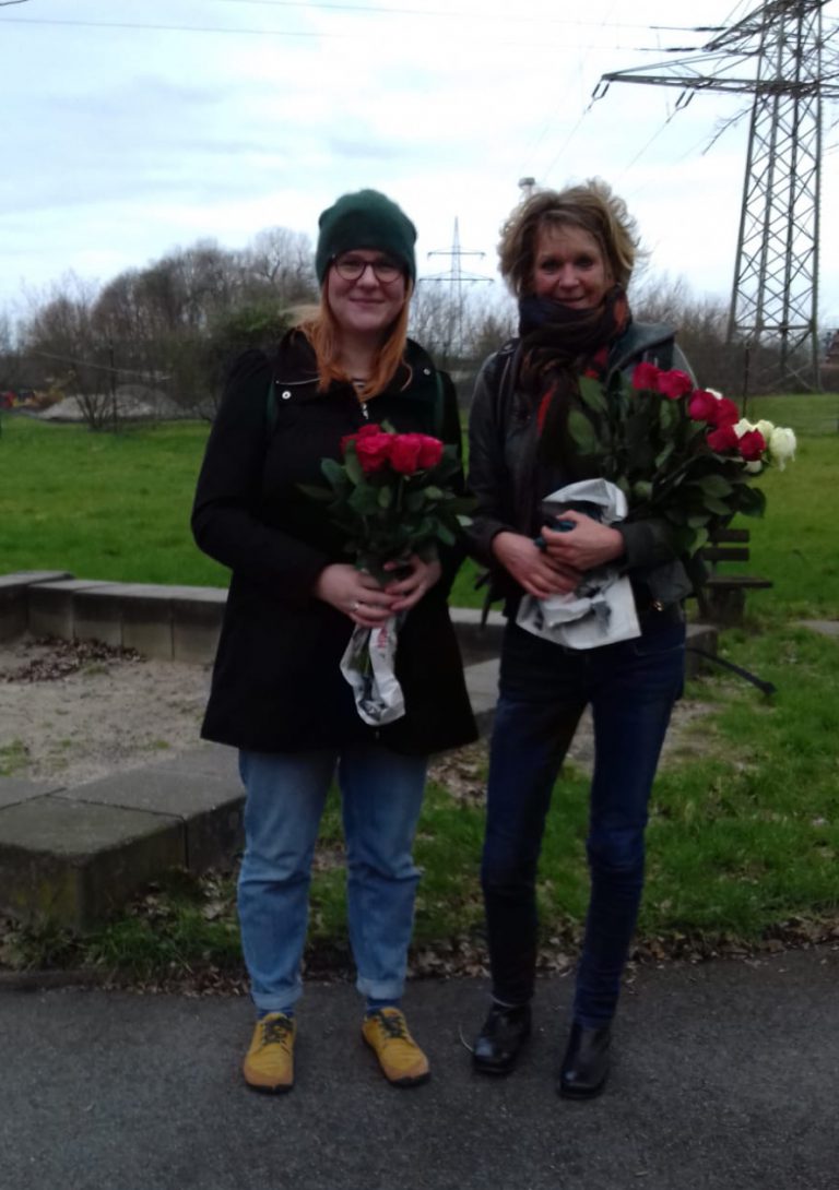 Grüne Frauen überreichen Flüchtlingsfrauen Blumen zum Frauentag