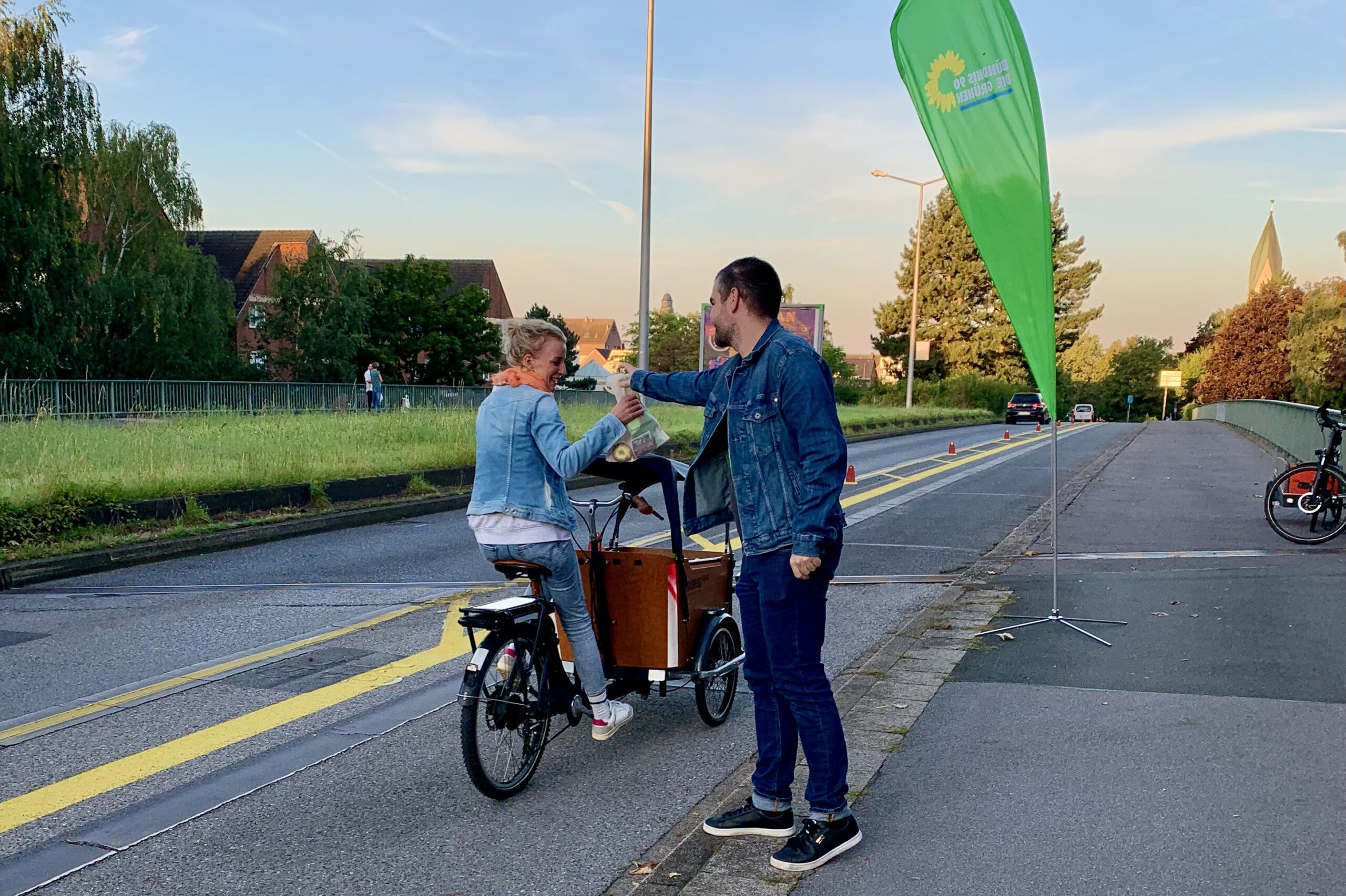 Frederic überreicht einer Radfahrerin auf einem Lastenrad einen Snackbeutel als Dankeschön